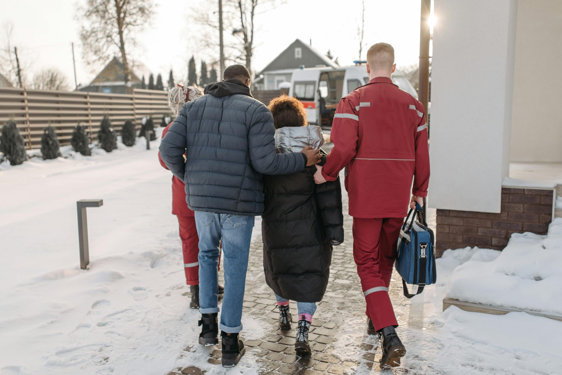 Sanitäter helfen im Winter Menschen auf einer verschneiten Straße zu einem Krankenwagen.