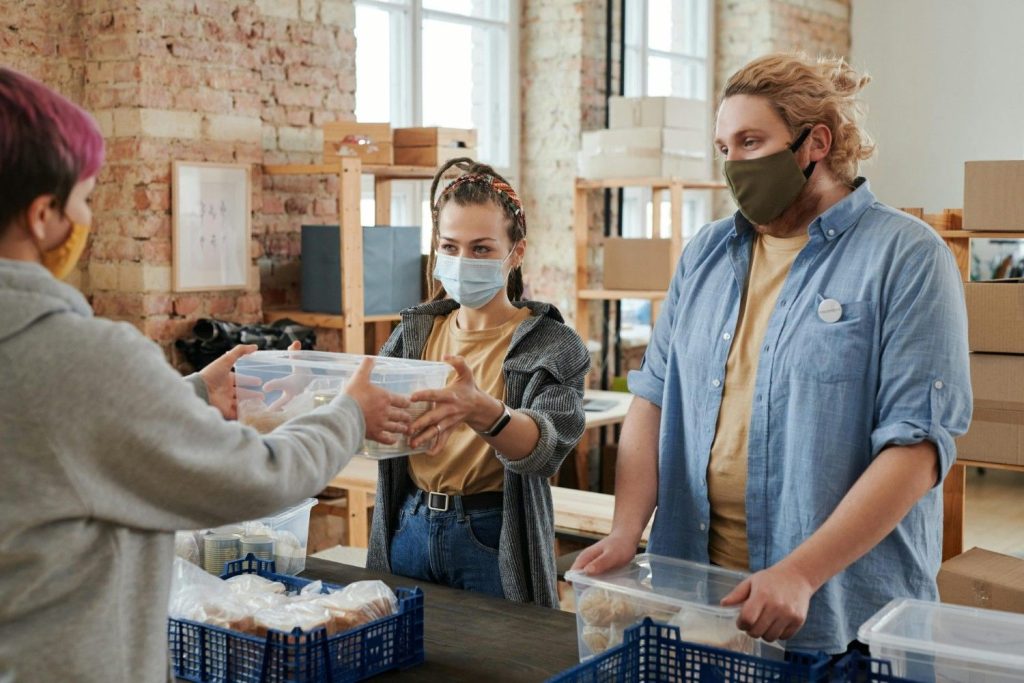 Freiwillige mit Masken verteilen Lebensmittel in einem Spendenzentrum und konzentrieren sich dabei auf Wohltätigkeit und Unterstützung der Gemeinschaft.